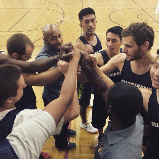 Tyndale basketball players standing in a circle team huddle