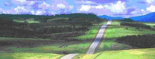 Landscape shot showing a vast expanse of hills some with trees and a road running through it