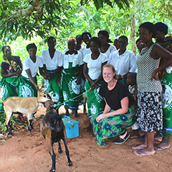 Kaitlyn Williams, a Tyndale student, in Malawi, crouching next to a couple of animals and surrounded by local Malawi residents