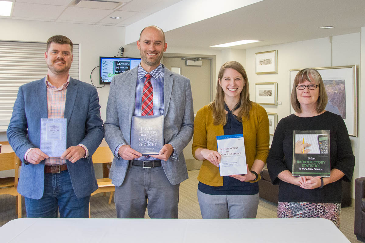 Four University College professors pose with their recently-published books