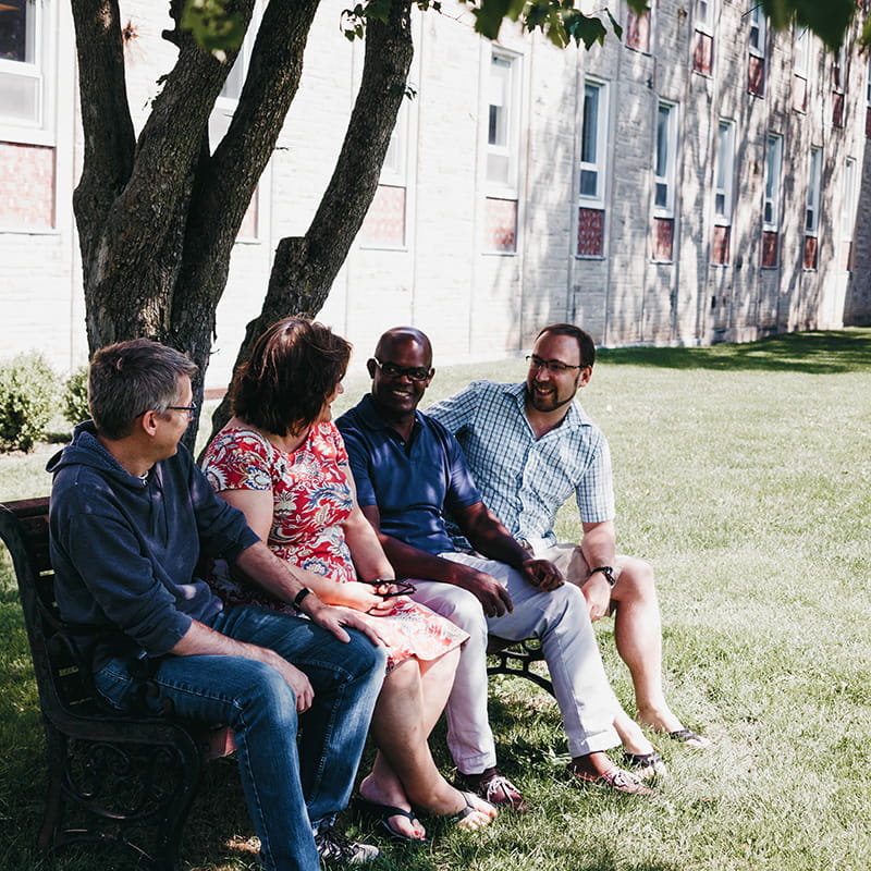 Four students sitting on a bench having a conversation.