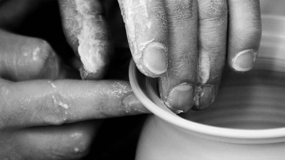 A potter's hand moulding a clay pot