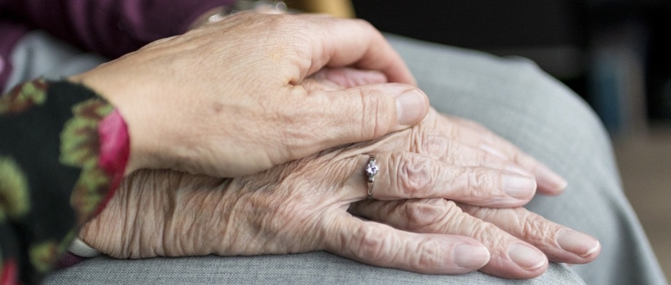 an elderly person's hand being held by a younger person's hand in sympathy 