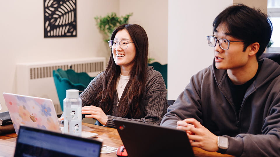 Students with their laptops in a conversation.