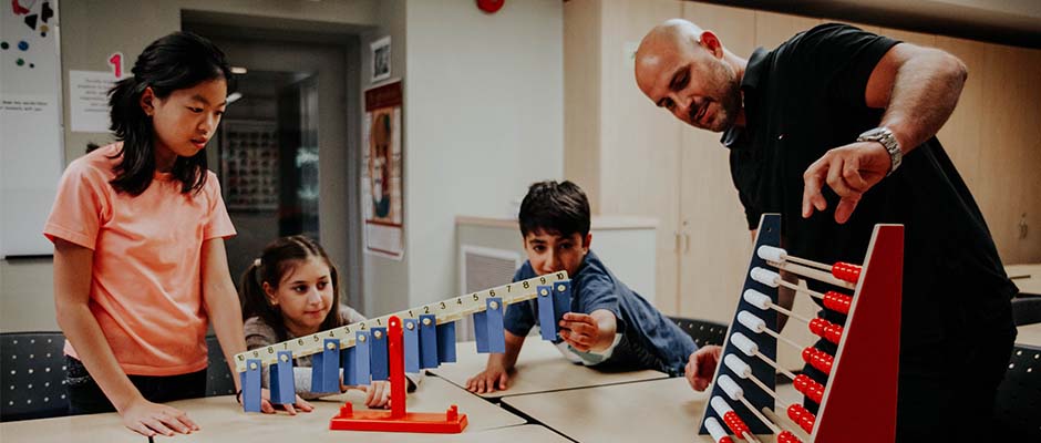 Male teacher teaches students math with a standard abacus
