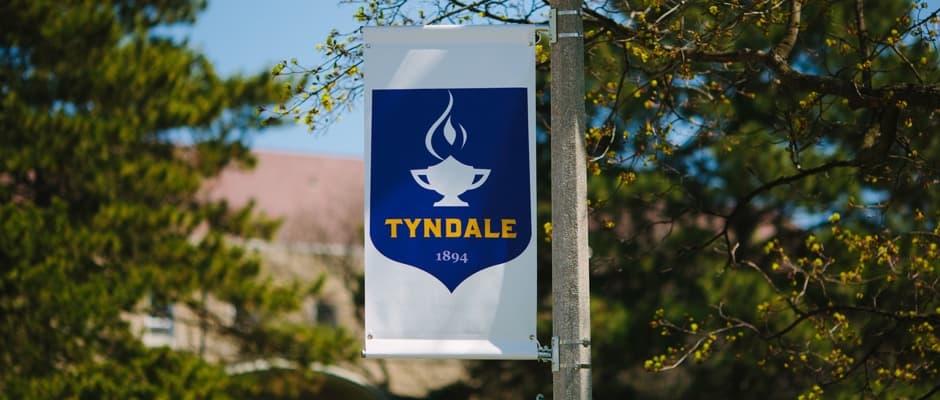 Tyndale crest on a flag hanging from a flagpole 