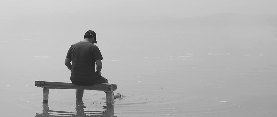 grayscale photo of man sitting on dock photo