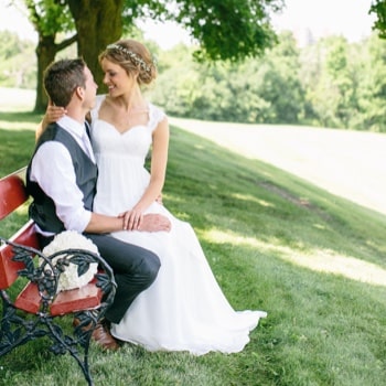 a bride and groom sitting on a bench outdoors