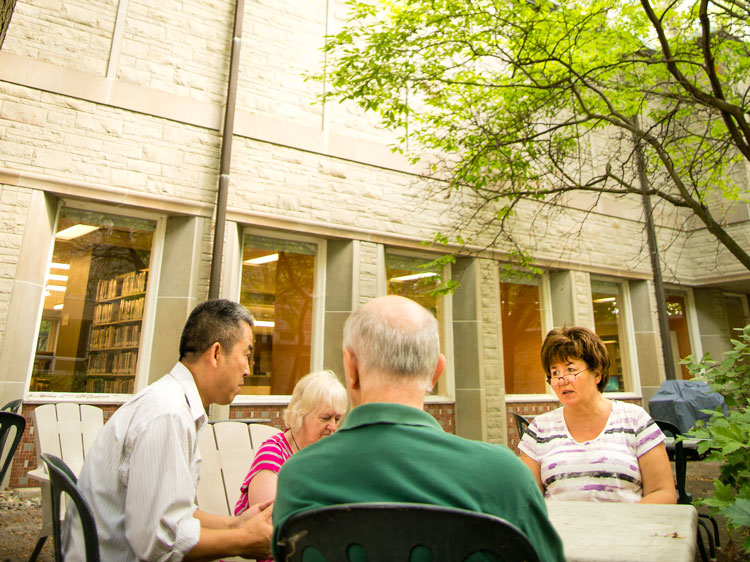 A group of older adults having a retreat in the courtyard.