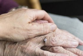 an elderly person's hand being held by a younger person's hand in sympathy 