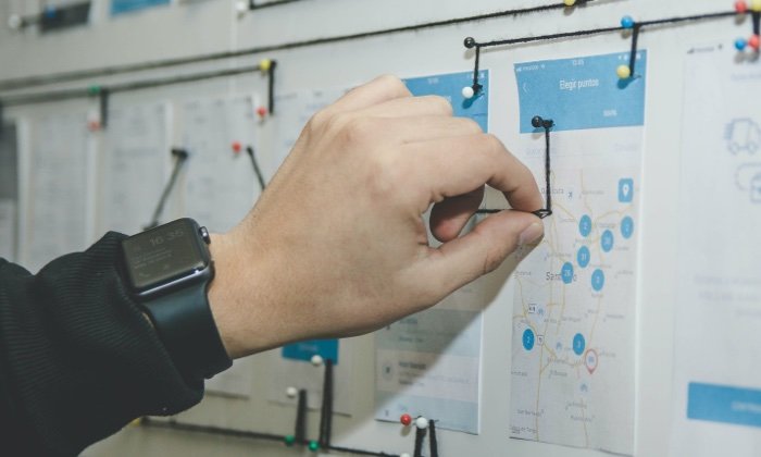 person's hand pinning a flowchart on a pin board