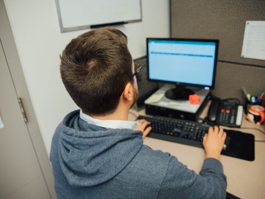 a student in an office working at a computer. 