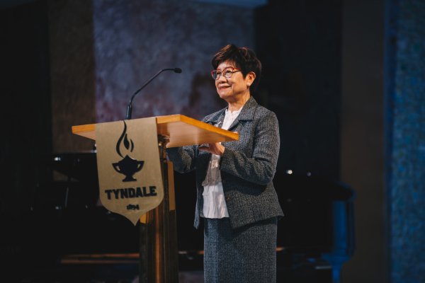 Woman speaks at podium, Esther Chan gives speech