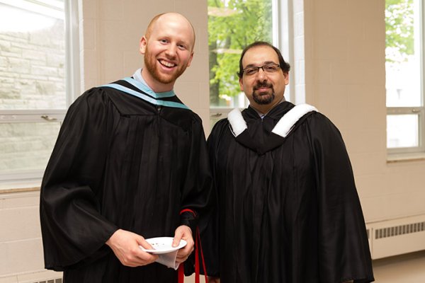 A graduate posing with a faculty member