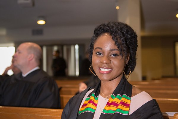 A graduate sitting in the pew smiling