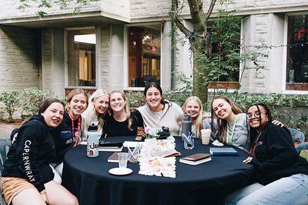 Eight smiling students sitting around a table
