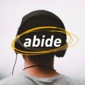 A man wearing headphones with the word abide