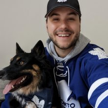 Joel Erhardt in a Toronto Maple Leafs jersey sitting next to a dog also in a Leafs jersey