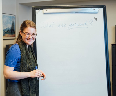 a tutor with a marker standing in front of a white board, smiling. 